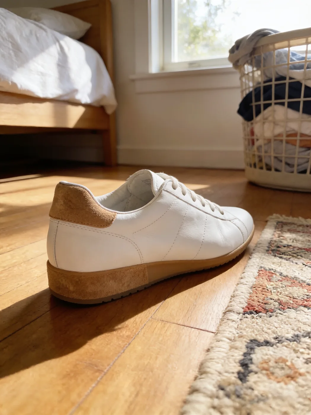 A white sneaker on a wooden bedroom floor next to a rug
